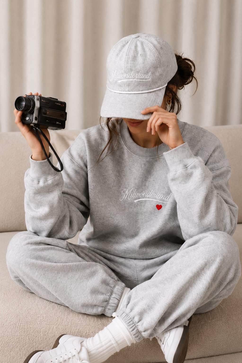 Woman in the grey Milwonderland club set holding a vintage camera