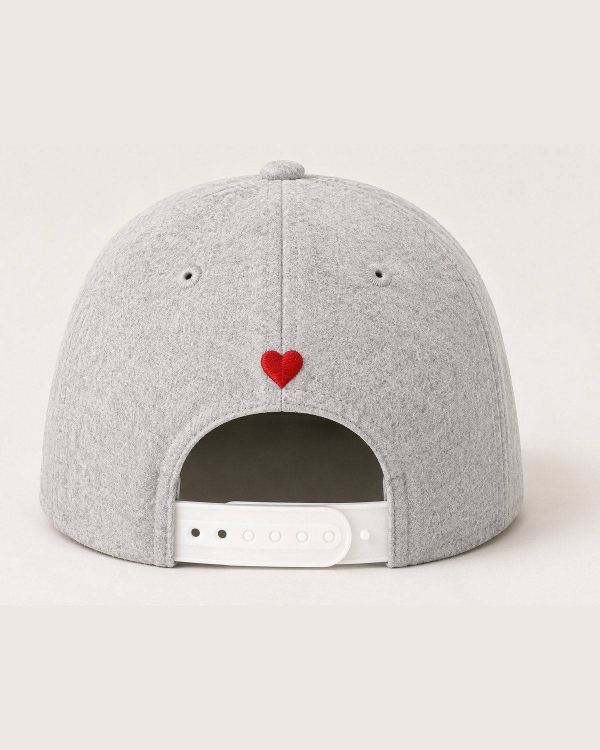The back of the light grey cap: the snapback and a small red heart.